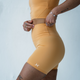 A woman wearing green orange blaze legging shorts and a sports crop top.