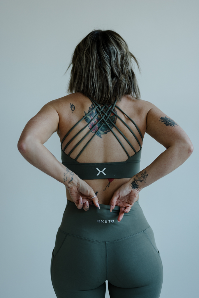 Person wearing a green sports bra and leggings with a plain background
