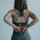 Person wearing a green sports bra and leggings with a plain background
