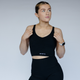 Woman wearing a black sports bra and shorts with a visible brand logo on a plain background