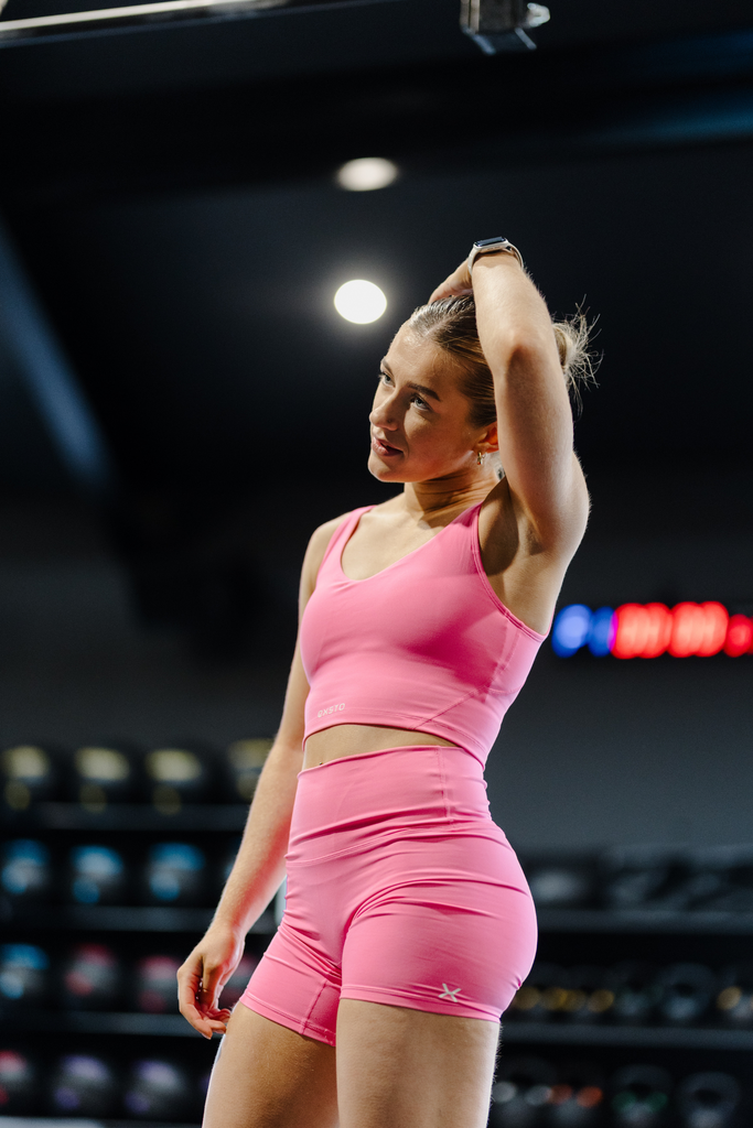 Woman in pink athletic wear exercising in a gym setting