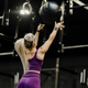 Woman in purple athletic wear lifting a medicine ball in a gym setting