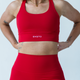 A person wearing a red high support cross back sports bra and matching red leggings.