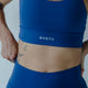 Woman wearing blue high support cross back sports bra for gym training